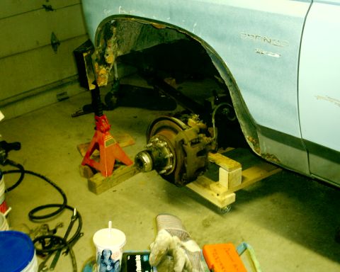 1985 Ford Bronco - The side of a light blue Ford Bronco is shown with extensive rust and damage to the wheel well, indicating it is undergoing repairs.