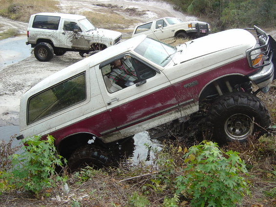 White and maroon Ford Bronco stuck in mud with two other SUVs in the background