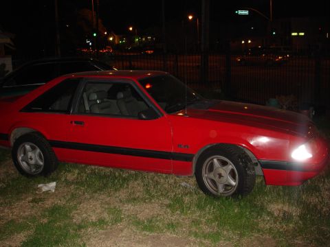 1993 Ford Taurus - Side view of a red coupe parked on grass at night.