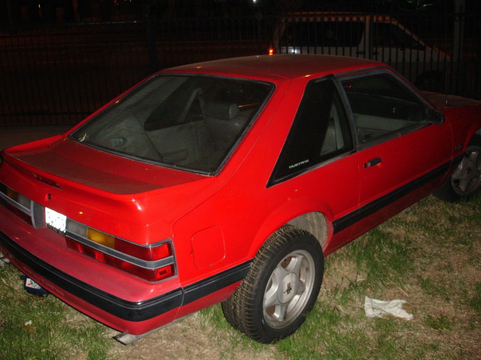 Red coupe with a black trim and a spoiler, seen from the rear quarter angle