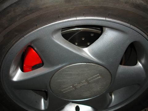 1993 Ford Taurus - Close-up of a car wheel with a red brake caliper and slotted rotor visible.