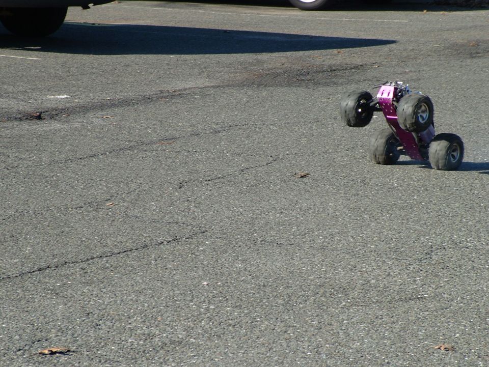 purple remote control monster truck on its side on asphalt