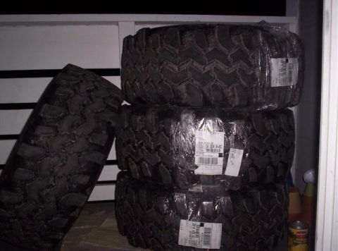 1987 Suzuki Samurai - Four new off-road tires are shrink-wrapped and stacked, with another tire leaning to the left.