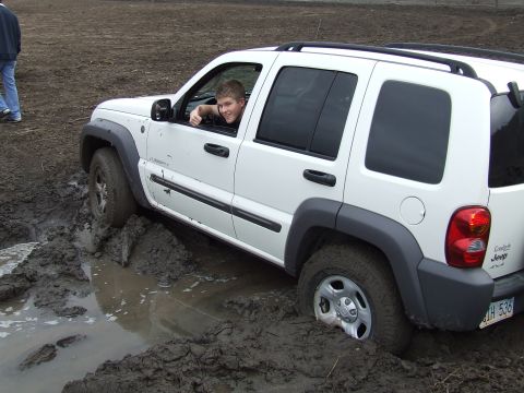 1994 Ford Bronco - Driver gives a thumbs up from inside a white Jeep Liberty stuck in deep mud.