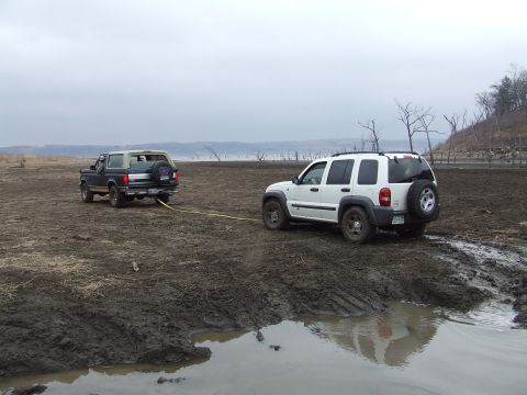 1994 Ford Bronco - Two SUVs are stuck in the mud, with one vehicle attempting to tow the other.