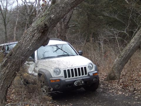 1994 Ford Bronco - White Jeep Liberty navigating rough terrain with another vehicle partially visible in the background.