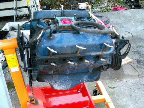1986 Ford Bronco - A blue V8 engine is mounted on an orange engine stand, ready for installation or work.