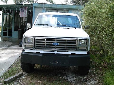 1986 Ford Bronco - This white Ford truck features a prominent aftermarket bumper and a classic grille design.