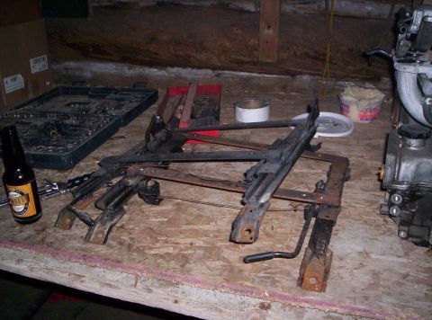 1993 Ford Probe - Two car seat frames are laid out on a workbench, alongside a bottle of beer and various tools.