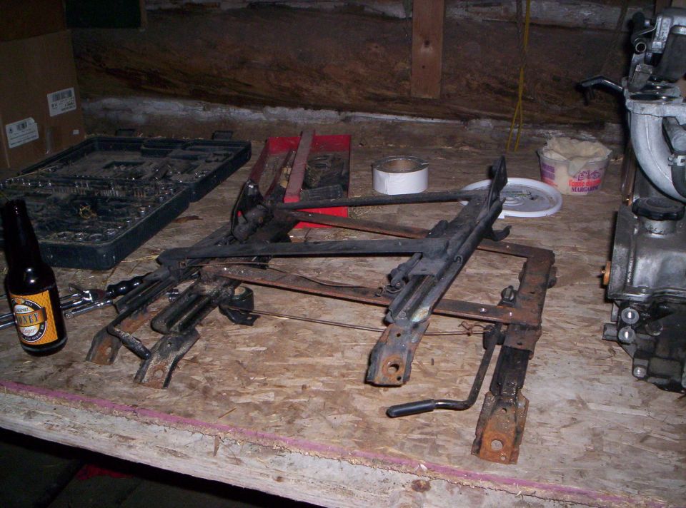 Car seat frames on a workbench with a beer bottle