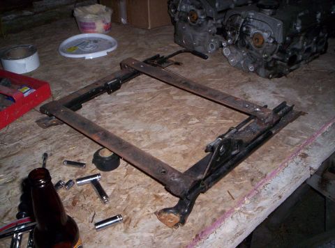 1993 Ford Probe - A disassembled car seat frame lies on a workbench with various tools and a partial beer bottle.