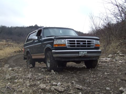 1994 Ford Bronco - This 1994 Ford Bronco is captured in a three-quarter front view, navigating a , rocky path.
