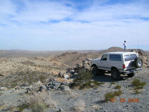 1985 Ford Bronco - White Ford Bronco parked on a rocky hill with a desert landscape in the background.