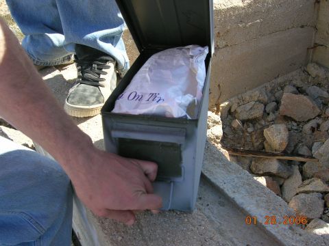 1985 Ford Bronco - An ammo can is opened, revealing a white bag with text on it, as a hand reaches inside.