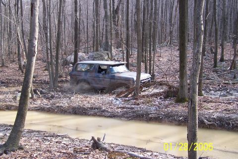 1979 Ford Bronco - A 1978 Ford Bronco drives through a muddy, wooded area, kicking up dirt.