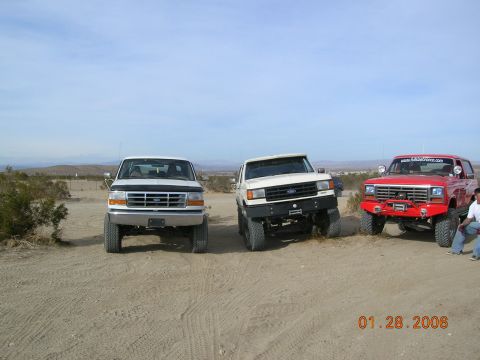 1985 Ford Bronco - Three Ford trucks are parked in a dusty outdoor area under a clear sky. The date 01.28.2006 is visible in the lower right corner.