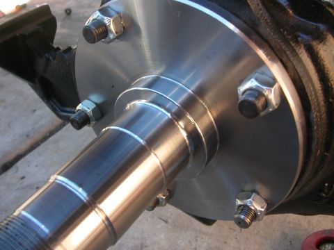 1984 Ford Bronco - Close-up of a vehicle hub and spindle assembly, showing lug nuts and threaded spindle.