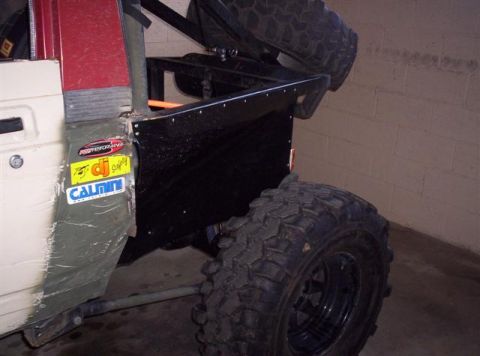 1987 Suzuki Samurai - A modified off-road vehicle's rear section is shown with various stickers on the side panel and a spare tire mounted overhead.