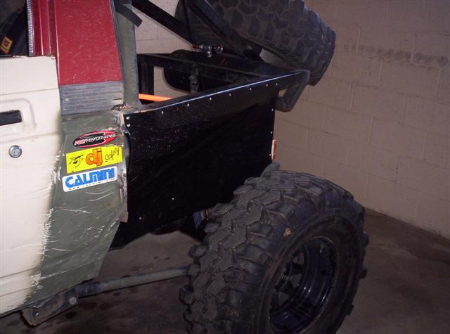 Off-road vehicle rear quarter panel with stickers and large mud tire, spare tire mounted above