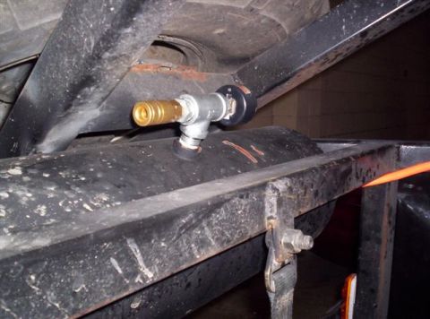 1987 Suzuki Samurai - Close-up view of an air fitting installed on a fuel tank, part of a vehicle's undercarriage.