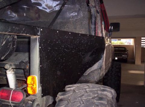1987 Suzuki Samurai - The rear section of a heavily modified off-road vehicle is shown, with another car parked in the background.