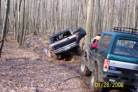 1979 Ford Bronco - Two Ford Broncos off-road in a wooded area, with one vehicle stuck in the mud.