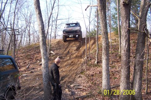 1979 Ford Bronco - An off-road truck navigates a challenging incline in a wooded area.