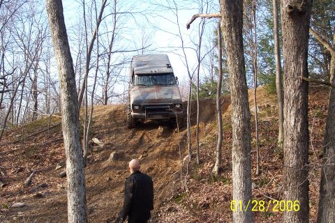 1979 Ford Bronco - An off-road van navigates a steep dirt incline, with a person watching from below. The vehicle appears to be a modified van, older model va…