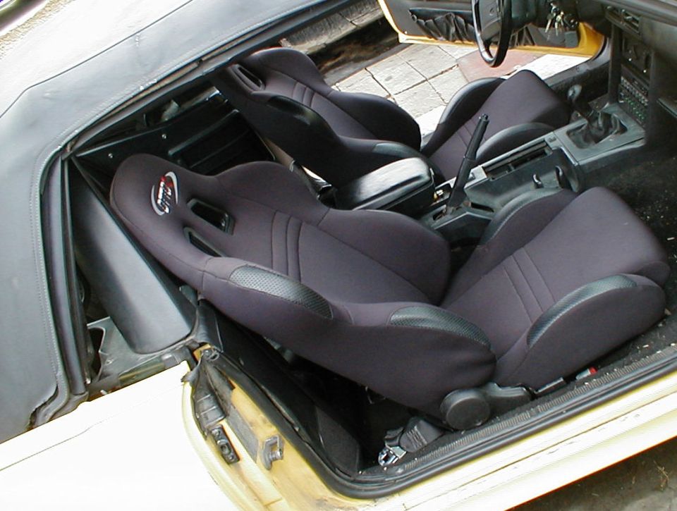 Yellow convertible interior with black aftermarket racing bucket seats and manual shifter