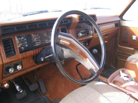 1978 Ford Bronco - The interior of a 1978 Ford Bronco features wood grain accents on the dashboard and steering wheel, along with an XLT badge.