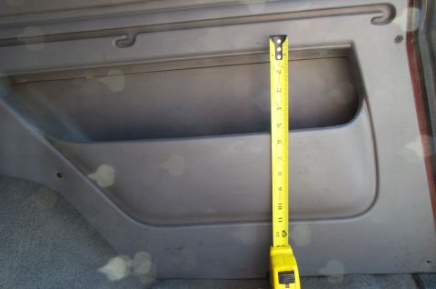 1996 Ford Bronco - A yellow tape measure is used to measure the depth of a vehicle's interior door pocket.