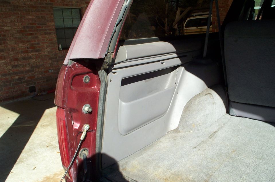 1996 Ford Bronco rear interior cargo area, showing side panel and carpeted floor. Another vehicle is visible in the background