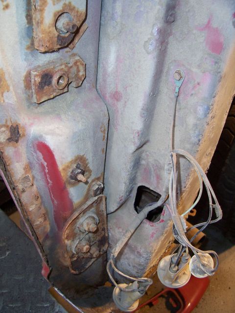 1978 Ford Bronco - Close-up of a stripped and partially sanded rear body pillar and quarter panel area showing bare metal, surface rust, and traces of red and…