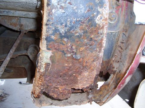 1978 Ford Bronco - Close-up of severe rust-through at the base of a rear body pillar, with flaking scale, perforated metal and a hole eaten through beside the…