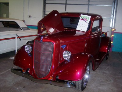 1972 Ford Ranchero - A shiny red 1935 coupe utility is displayed with its hood open, parked next to another vehicle.