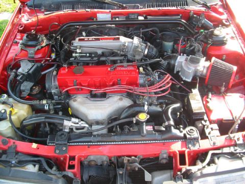1989 Mazda MX-6 - Engine bay detail of a red Mazda, likely from the late 80s or early 90s.
