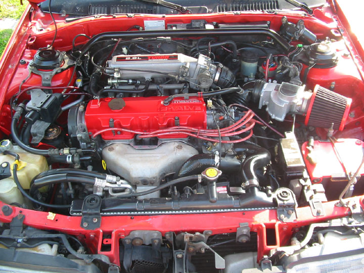 Engine bay with red valve cover, intercooler, cone filter and plug wires