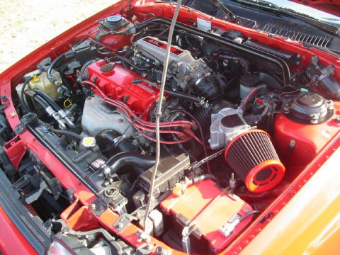 1989 Mazda MX-6 - Close-up view of a red engine bay, a 2.0L engine and an aftermarket air intake system.