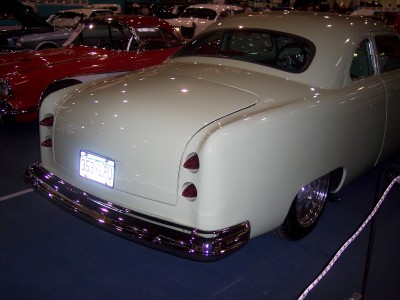 1972 Ford Ranchero - A pale yellow coupe is displayed indoors, with another red vehicle visible in the background.