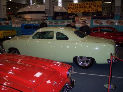 1972 Ford Ranchero - A light green coupe is displayed indoors, with a red car in the foreground and boats in the background.