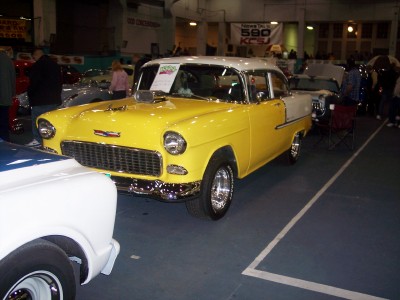 1972 Ford Ranchero - A yellow and white 1955 Chevrolet sedan is displayed indoors with other vehicles.