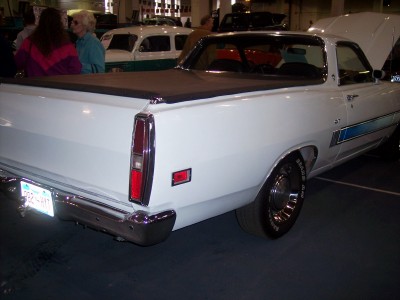 1972 Ford Ranchero - A white 1972 Ford Ranchero is displayed with its hood up, showing a blue side stripe and a black tonneau cover over the bed.