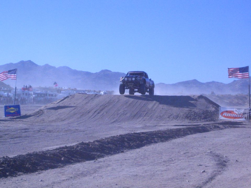 Off-road race truck airborne over a dirt jump in the desert
