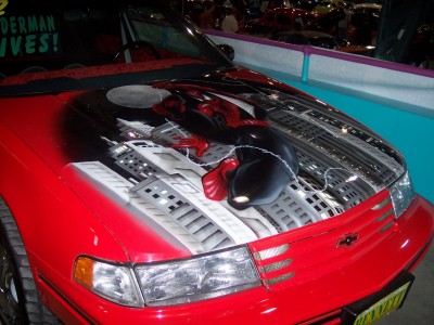 1972 Ford Ranchero - A red car features a custom airbrush mural of Spiderman on its hood, with the text 'SPIDERMAN LIVES!' visible on the windshield.