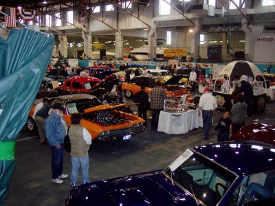 1972 Ford Ranchero - An indoor exhibition hall filled with various cars and attendees, suggesting a car show or convention.