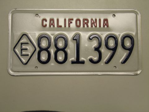 1991 Ford LTD Crown Victoria - single white California license plate reading 881399 with an E-in-diamond emblem on a gray-green surface.