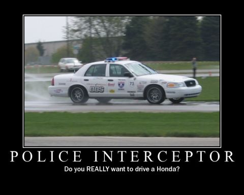 1998 Ford Crown Victoria - A 1998 Ford Crown Victoria police car drives on a wet track, spraying water.