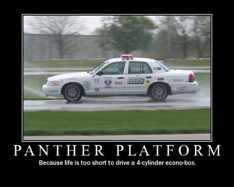 1998 Ford Crown Victoria - A white police car with racing decals and BBS wheels is seen on a wet track, possibly during a race or practice session.