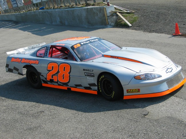 Silver 2005 Chevrolet Monte Carlo race car with orange stripes and number 28