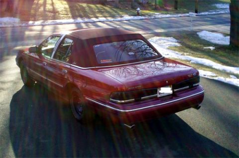 2000 Ford Crown Victoria - A red convertible sedan is shown from the rear three-quarter angle. The vehicle's body style suggests it is from the early 1990s.